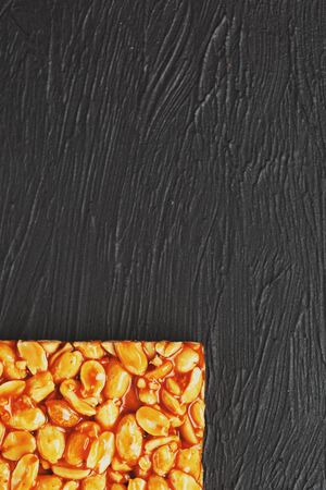 Golden boletus kozinaki from roasted peanut beans energy bars. Black textural background, top view. Copy space, useful snacks. Fitness diet food, super food. In low keyの写真素材
