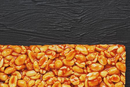 Golden boletus kozinaki from roasted peanut beans energy bars. Black textural background, top view. Copy space, useful snacks. Fitness diet food, super food. In low keyの写真素材