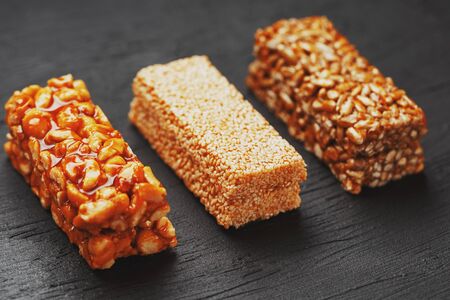 Healthy snacks. Fitness diet food. Grain bar with peanuts, sesame and seeds on a cutting board on a dark table, energy bars. Black background top view. Isolate, Copy Spaceの写真素材