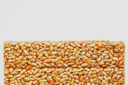 A large golden tile of sunflower seeds, a bar in a sweet molasses on a white background. Kozinaki...