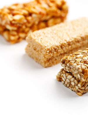 Grain granola bar with peanuts, sesame and seeds in a row on a white background. Top view Kozinaki Three assorted bars, isolateの写真素材