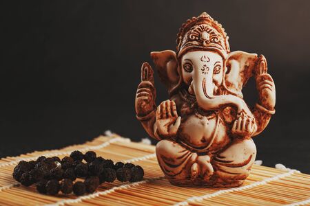 Hindu god Ganesh on a black background. Statue with incense smoke aromo sticks. Copy spaceの写真素材