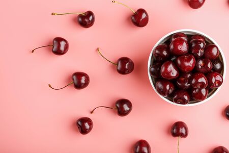 Cherry berry on a pink background in a white cup, top view. Concept of fertilization.の写真素材