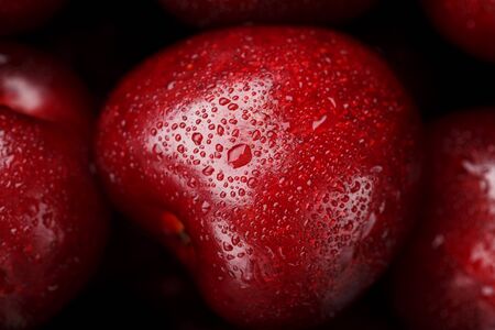 Ripe and fresh berries of a sweet cherry with water drops closeup. Cherry in the shape of a heart. Macroの写真素材