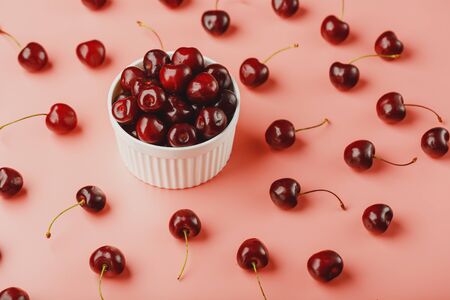 Cherry berry on a pink background in a white cup, top view. Concept of fertilization. Low contrastの写真素材