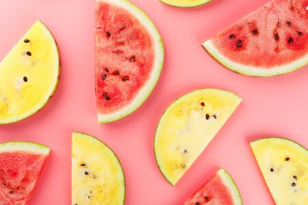 Juicy slices of red and yellow watermelon on a bright pink background. Conceptual colors of summer. Patterns top view as a background or substrate, wallpaperの写真素材