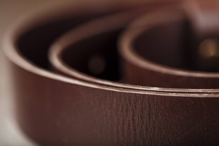 Fashionable men's brown belt made of genuine leather with a light metal buckle on a dark background. Genuine leather, handmade. Close-upの写真素材