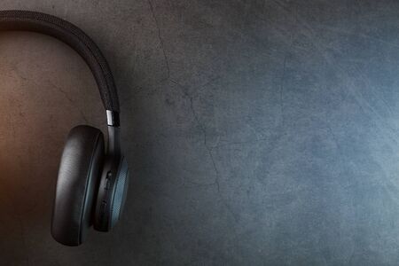 Wireless black headphones on a dark background with blue and orange backlight. On-ear headphones for playing games and listening to music tracks. Modern styleの写真素材