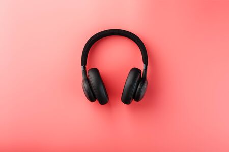 Wireless black headphones on a pink background. On-ear headphones for playing games and listening to music tracks. View from above. Modern style and colorの写真素材
