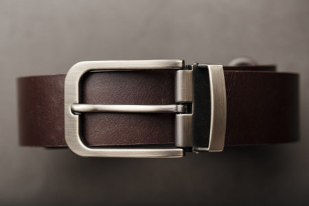 Fashionable men's brown belt made of genuine leather with a light metal buckle on a dark background. Genuine leather, handmade. Close-upの写真素材