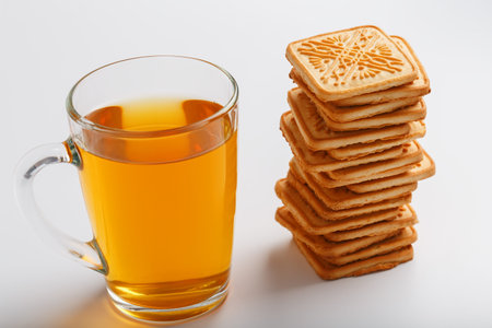 A stack of golden wheat cookies and a mug of fragrant green tea in on a white background. Cookies...