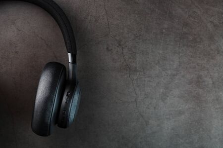 Wireless black headphones on a dark background with blue and orange backlight. On-ear headphones for playing games and listening to music tracks. Modern styleの写真素材