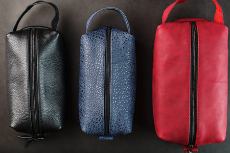 Three bags, black, blue and red with genuine leather locks on a black background. Handwork, View from aboveの写真素材