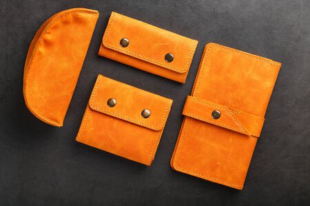 A set of purse, bag, part man, case for glasses and a key holder, made of genuine leather on a dark background. Elements of leather craft products handmade. Handmade rivets and seam Close-upの写真素材