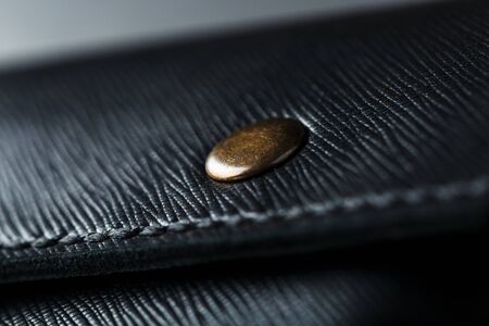 Black wallet made of genuine leather on a dark background. Handmade leather items. Rivets and seam close upの写真素材
