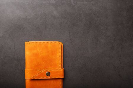 Wallet made of genuine brown leather on a dark background. Handmade leather items. Handmade rivets and seam closeupの写真素材