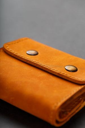 Brown purse, wallet made of genuine leather on a dark background. Elements of leather craft products...