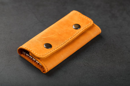 Key wallet made of genuine brown leather on a dark background. Handmade leather items. Handmade...