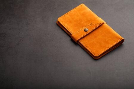 Wallet made of genuine brown leather on a dark background. Handmade leather items. Handmade rivets and seam closeupの写真素材