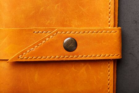 Wallet made of genuine brown leather on a dark background. Handmade leather items. Handmade rivets and seam closeupの写真素材