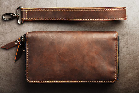 Organizer wallet made of brown Genuine leather, handmade on a dark background. Close-up, castle and...