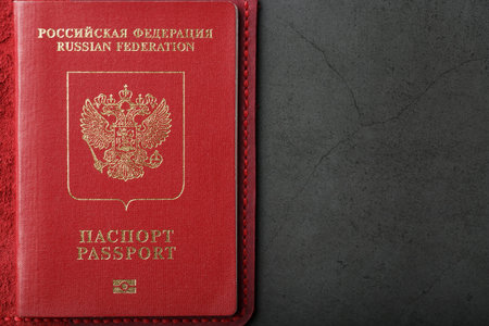 Red passport cover made of genuine leather handmade on a dark background. Passport of a citizen of...