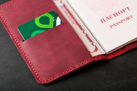 Red handmade passport cover made of genuine leather on a dark background, revealed with a passport and a green electronic card. Passport of a citizen of the Russian Federation. Close-up.の写真素材