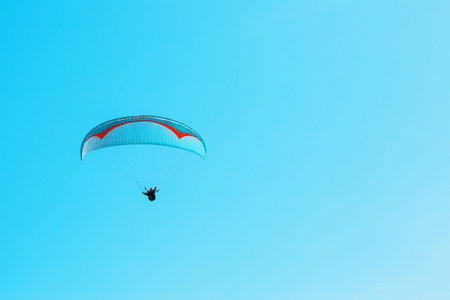 Paraglider soars against the blue sky with clear space. Place for text