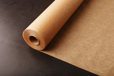 A roll of unfolded brown parchment paper, for baking food in on a dark background, top view. Papyrusの写真素材
