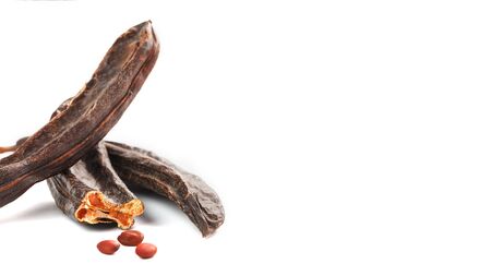 Carob carob fruit and seeds on white background. Isolate. Organic carob beans, a healthy alternative to cocoa. Free spaceの写真素材