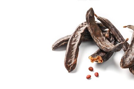 Carob carob fruit and seeds on white background. Isolate. Organic carob beans, a healthy alternative to cocoa. Free spaceの写真素材