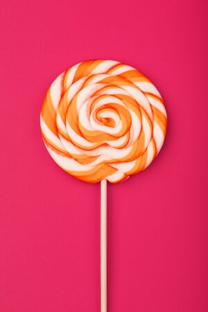 A large yellow Lollipop, on a scarlet background. Minimal concept with copy space. Confectionery products, Goodiesの写真素材