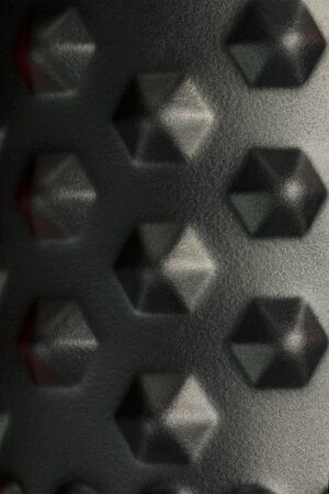 Black lumpy foam massage roller on red background. For the mechanical and reflex effects on tissues and organs. Close-up, texture, element in macroの写真素材