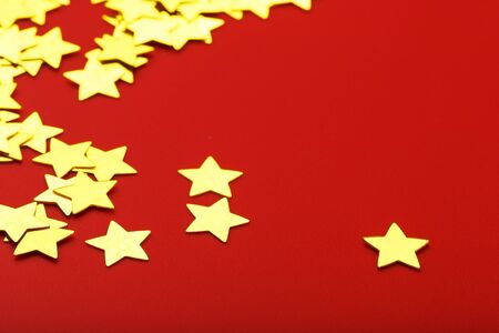 A scattering of Gold stars on a red background. Greeting cards, headlines and website concept. Top view, close-upの写真素材