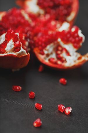 The opened Fruits of a ripe open pomegranate lie on a black textural background. The view from the topの写真素材