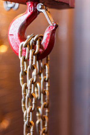 metallic chain handle with red hook in technical room. Crane cargo hook. Concept of maintenance and...