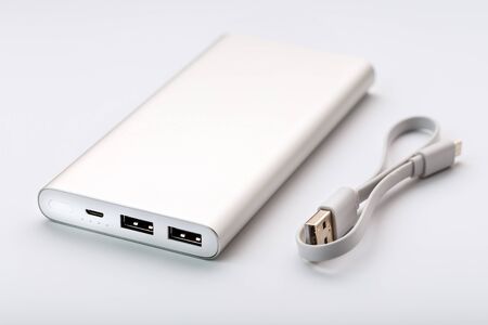 Powerbank for charging mobile devices with cable, on a white background. Universal external battery for gadgets. Isolateの写真素材
