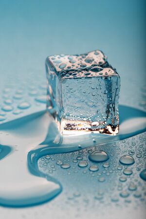 Ice cube with water drops on a blue background. The ice is melting. Refreshing ice.の写真素材