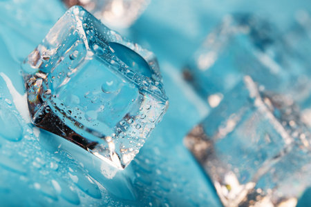 Ice cubes are scattered with water drops scattered on a blue background. Close up. Refreshing ice.