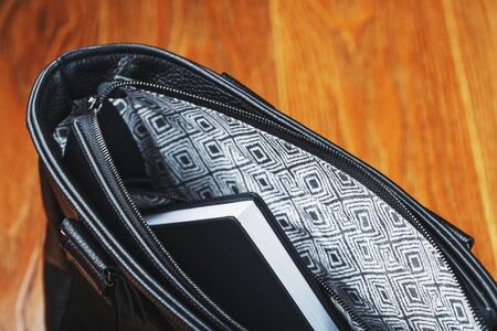 Black notebook peeking out of the pocket of a black leather bag close-up, macro Handmade, natural materials. Design products, Hobbies, and businesses.の写真素材