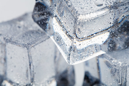 Ice cubes in the form of a pyramid with water drops close - up in macro on a white background. Refr