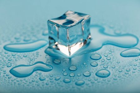Ice cube with water drops on a blue background. The ice is melting. Refreshing ice.の写真素材