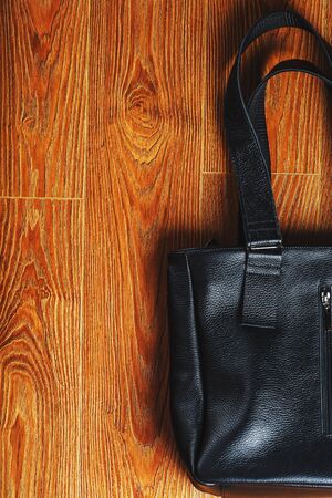 Handmade black leather bag on a wooden background, made of natural material. Design, Hobbies and businesses.の写真素材