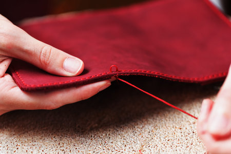 Conceptual profession of a Tanner. The woman's hands closed around the needle and thread. The master sews the skin. Handmade work.の写真素材