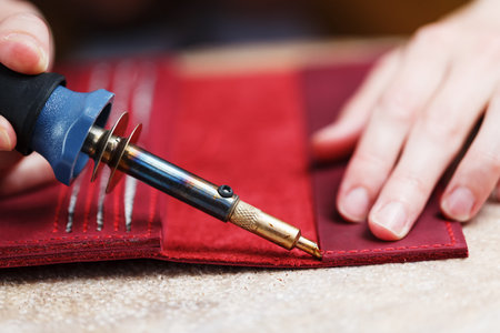 A leather craftsman works with leather. Sews leather goods. Making things handmade. Women's hands...