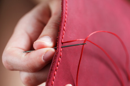 Conceptual profession of a Tanner. The womans hands closed around the needle and thread.