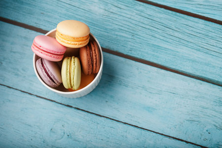 Macaroni cookies are placed in a white plate on a blue wooden background. Free space, top View. The concept of minimalismの写真素材