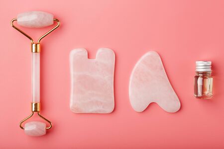 Gua sha massage tool made of natural pink Quartz-roller, jade stone and oil, on a pink background for face and body care. Horizontal shoot. Flat lay, top view. Copy space for your text.の写真素材