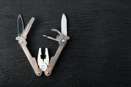 Multitool is a multi-functional tool on a black background. The concept of an expanded multi-tool...