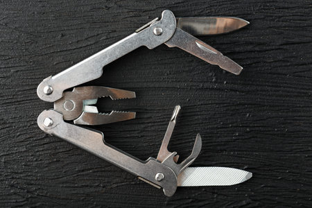Multitool is a multi-functional tool on a black background. The concept of an expanded multi-tool...